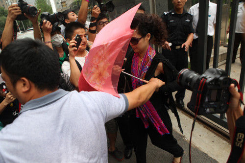 7月22日下午5点左右，李天一涉嫌轮奸一案庭前会议结束，其母亲梦鸽离开海淀区法院，依旧戴着黑色墨镜，以伞遮面只字未提。王黎/图