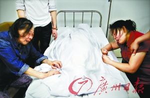 亮亮的身体用白布遮着，奶奶和妈妈伏在床边，悲痛欲绝。记者苏俊杰摄